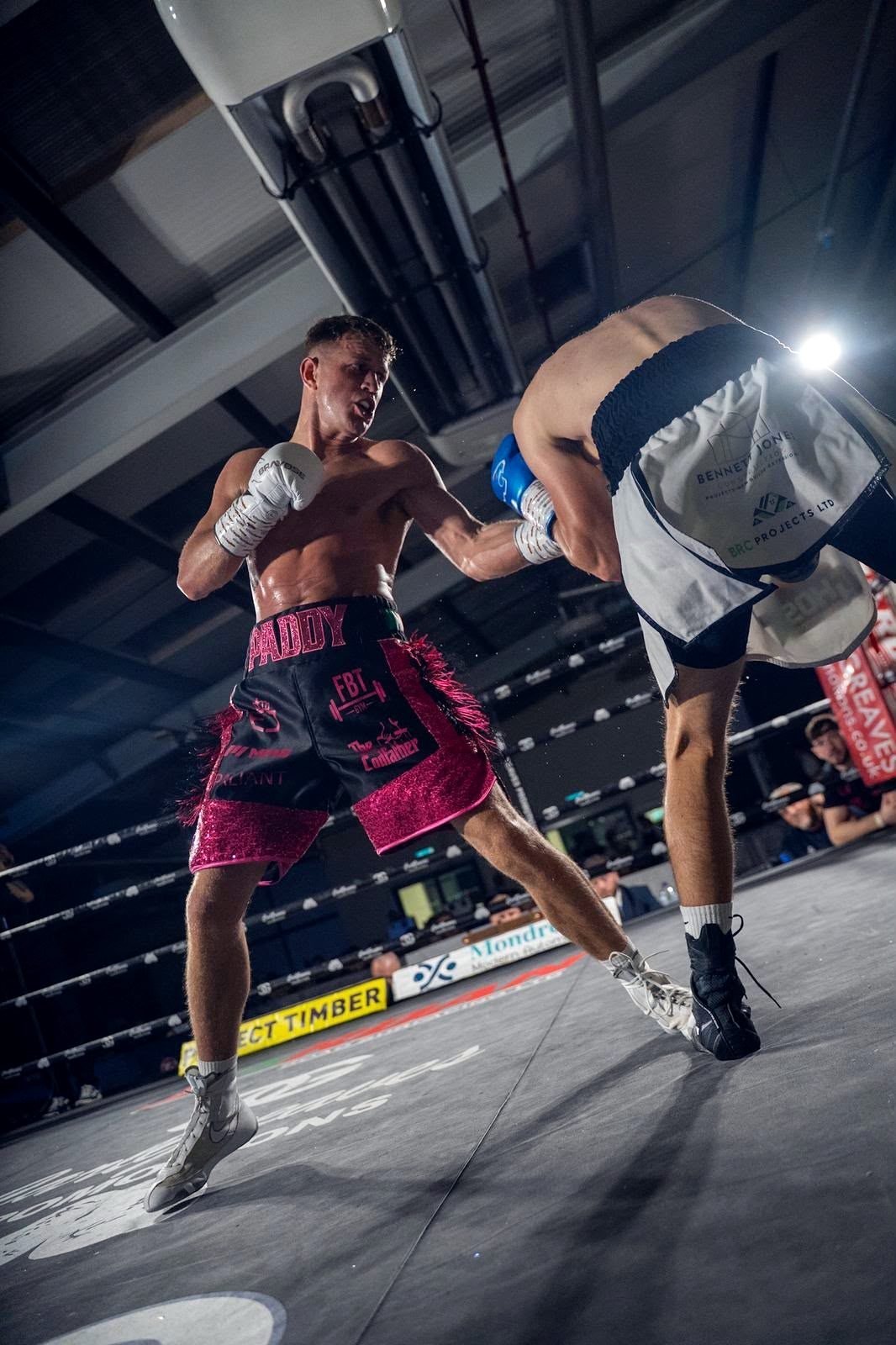 Paddy Walsh in pink and black shorts exchanging punches at close range