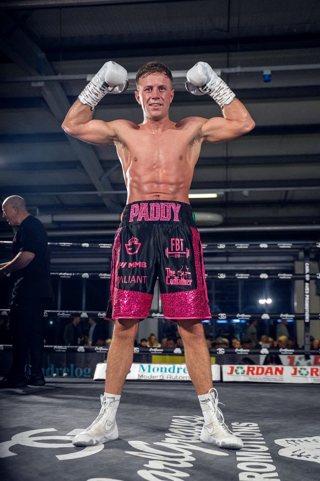 Paddy Walsh posing with raised gloves in pink and black shorts after a win